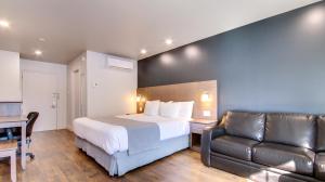a hotel room with a bed and a leather couch at Hôtel Marineau Shawinigan in Shawinigan