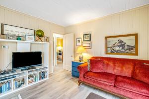 ein Wohnzimmer mit einem roten Sofa und einem TV in der Unterkunft Salt Water Cottage in Gearhart
