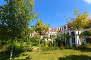 un grand bâtiment blanc avec un chien dans la cour dans l'établissement Fort Noks - Menada Apartments, à Sveti Vlas
