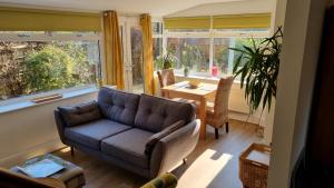 a living room with a couch and a table and windows at Garden Cottage - Ashover Village near Matlock in Chesterfield