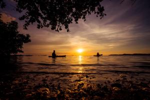 twee mensen in boten in het water bij zonsondergang bij Cocovana Beach Resort in Busuanga