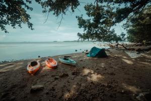 three kayaks and a tent on a beach at Cocovana Beach Resort in Busuanga