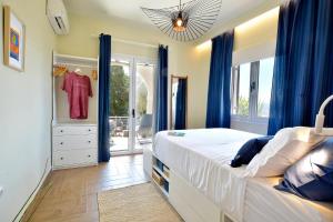 een slaapkamer met een bed met blauwe gordijnen en een dressoir bij Kommeno Blue Bay Apt. in Kommeno