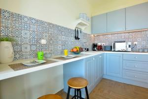 una cocina con armarios azules y una barra con taburetes en Kommeno Blue Bay Apt., en Kommeno