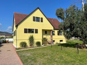 una casa amarilla con techo rojo en Alsacebnb - Gîte 12 personnes dans le vignoble - Piscine privée chauffée & Spa, en Ammerschwihr