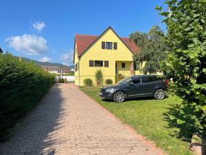 a car parked in front of a yellow house at Alsacebnb - Gîte 12 personnes dans le vignoble - Piscine privée chauffée & Spa in Ammerschwihr