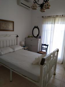 een slaapkamer met een wit bed en een stoel bij Traditional House Marivilla in Mastichari