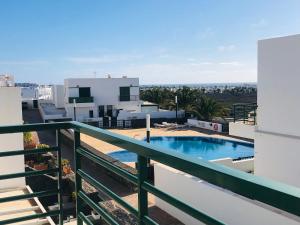 ein Balkon mit einem Swimmingpool auf einem Gebäude in der Unterkunft Alegranza, apartamento de 3 habitaciones en Lanzarote in Costa Teguise