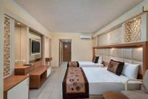 a hotel room with two beds and a television at Oz Hotels Incekum Beach in Alanya