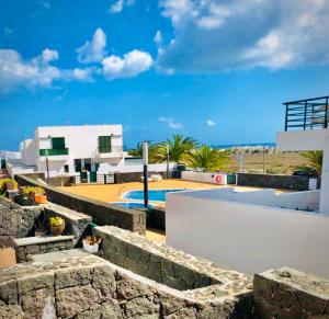 ein Haus mit einer Steinmauer und einem Pool in der Unterkunft Alegranza, apartamento de 3 habitaciones en Lanzarote in Costa Teguise