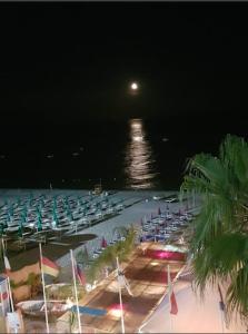 a beach at night with chairs and a full moon at Hotel San Pietro in Letojanni