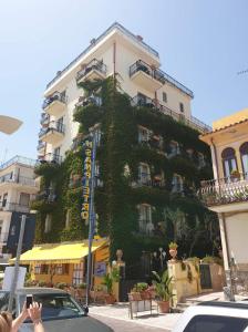 a building covered in ivy with cars parked in front of it at Hotel San Pietro in Letojanni