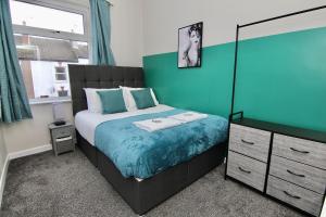 1 dormitorio con cama y pared azul en Stylish 4Bed Retreat - Walk to Coventry's Delights, en Coventry