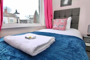 a bedroom with a bed with a blue blanket and a window at Mount Haven's Rest - Free Parking, Netflix & Private Back Garden in Coventry