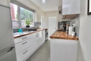 a kitchen with white cabinets and a large window at Stylish 4Bed Retreat - Walk to Coventry's Delights in Coventry