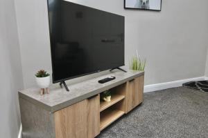 a flat screen tv sitting on top of a wooden entertainment center at Stylish 4Bed Retreat - Walk to Coventry's Delights in Coventry