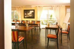 a dining room with tables and chairs and a window at Runas Air Muc Park Sleep & Fly in Hallbergmoos