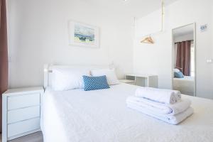 ein weißes Schlafzimmer mit einem weißen Bett und Handtüchern darauf in der Unterkunft Atlantic Breeze Apartments in Albufeira