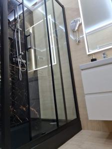 um chuveiro com uma porta de vidro na casa de banho em "Arkadia" em Ostrołęka