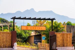 a sign for a garden with mountains in the background at Zostel Plus Lonavala in Lonavala