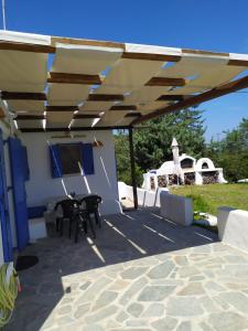 een terras met een tafel en stoelen onder een luifel bij Traditional House Marivilla in Mastichari +10 foto's