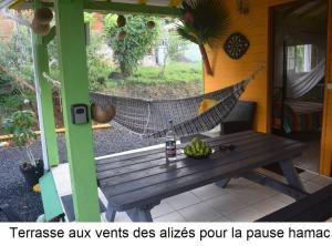 een hangmat op een veranda met een houten bank bij Gite à 2 pas de la flamboyante plage de La Perle in Deshaies