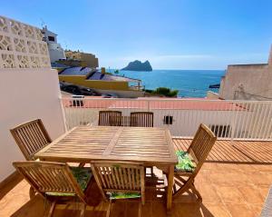 una mesa de madera y sillas en un balcón con vistas al océano en La Paloma, Chalet a pie de playa, en Águilas