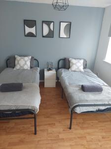 two beds in a room with wooden floors at Mornington Place in London