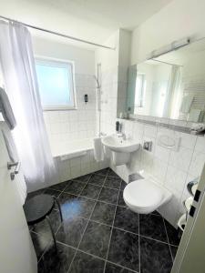 a bathroom with a sink, toilet, and bathtub at Air Muc Park Sleep & Fly in Hallbergmoos