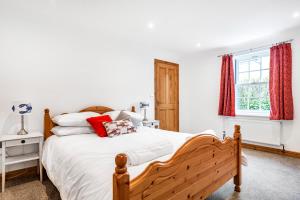 una camera da letto con un letto con lenzuola bianche e tende rosse di Eveley Cottage a Boscastle