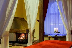 a bedroom with a fireplace and a bed and a window at Castle Hotel Daniel in Baraolt