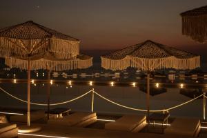 a pool with umbrellas next to the water at night at Maya Beach Resort in Massa Lubrense