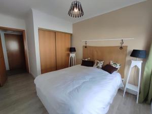 1 dormitorio con 1 cama blanca grande y 2 lámparas en City Apartament en Ponta Delgada
