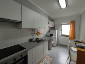 una cocina con armarios blancos y fregadero en City Apartament en Ponta Delgada