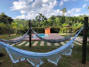 uma rede de descanso num jardim junto a uma piscina em Pousada Vale dos Sonhos em Cunha