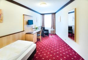 a hotel room with a bed and a desk at Hotel Gumberger GmbH Garni in Neufahrn bei Freising