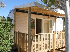a tiny house on a deck with a porch at Camping Pleine Mer in Vias