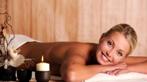 a woman laying on a bed with a candle at Appartementhaus Nürnberg in Bad Füssing