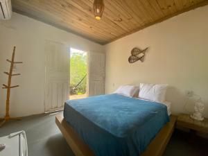 a bedroom with a blue bed and a window at Beco do Pescador in Caraíva
