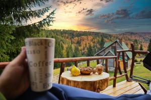 a person holding a cup of coffee on a deck at Eko Katun Bungalows Jelovica in Berane