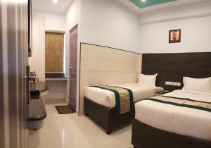 a hotel room with two beds and a window at Saibala Budget Airport Hotel in Chennai