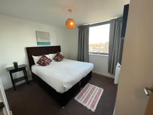 a bedroom with a bed with pillows and a window at Stratford Luxury Apartments in London