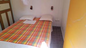 um pequeno quarto com uma cama com um cobertor colorido em Appartement de 2 chambres avec vue sur la mer jardin et wifi a Capesterre de Marie Galante em Capesterre