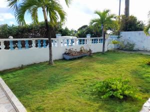 uma cerca branca com palmeiras num quintal em Appartement de 2 chambres avec vue sur la mer jardin et wifi a Capesterre de Marie Galante em Capesterre