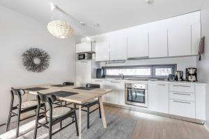 SuomutunturiにあるHoliday Apartments Suomu Chalet 14 A & Bの白いキャビネット、木製テーブルと椅子付きのキッチンが備わります。