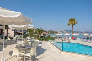 a hotel patio with a pool and tables and chairs at Xenos Kamara Beach in Argasi