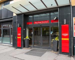 un edificio con puertas rojas y señales rojas en él en Thon Hotel Terminus en Oslo