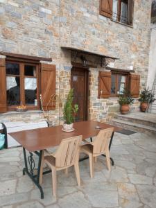 a wooden table and chairs on a stone patio at Kirmilis Mansion in Makrinítsa