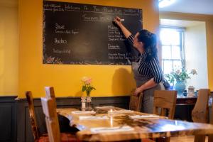 a woman writing on a chalkboard in a restaurant at Black Bull in Lauder