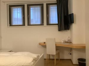um quarto com uma secretária, uma cama e janelas em Foresteria Gavazzeni em Bérgamo